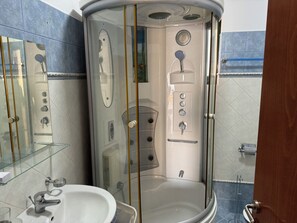 A modern bathroom with a glass-enclosed shower, a sink, and a toilet. - Spacious 3 Bedroom Apartment with Stunning Sea View (Saranda)