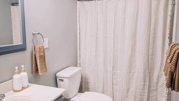 A bathroom with a white toilet, a sink with a mirror, and a shower curtain.
