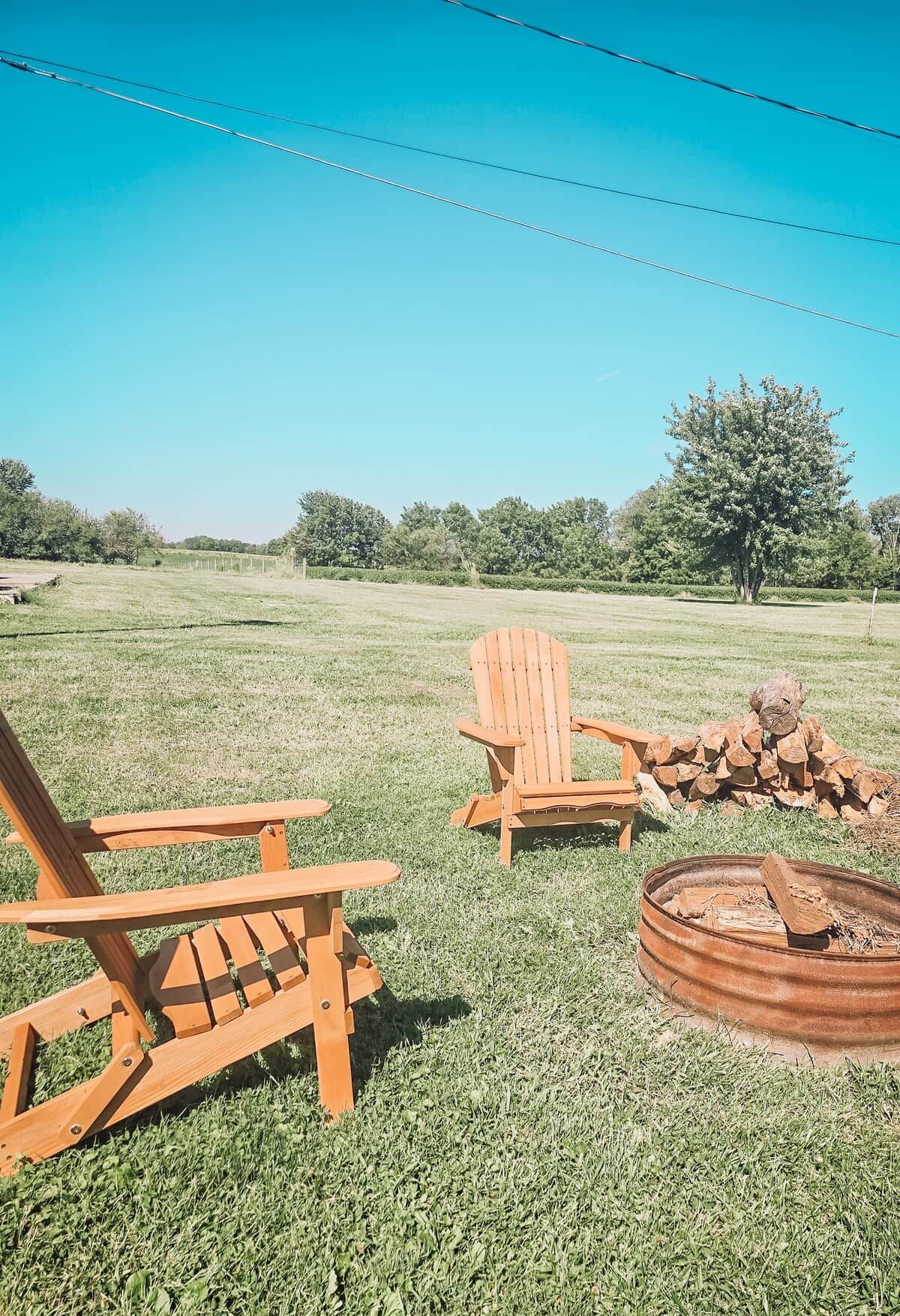 Un espacio de estar al aire libre con sillas de madera y un hoyo para la fogata.