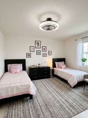A bedroom with two beds, a dresser, a nightstand, a lamp, and framed pictures on the wall. - Pleasant 3-bedroom barn with AC in Cape Coral (Cape Coral)