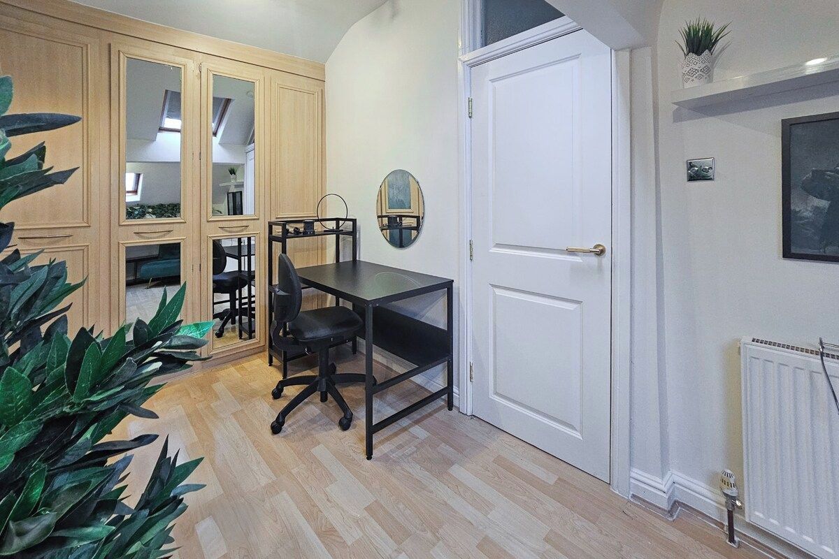 Una habitación con un armario de madera, un escritorio con silla, una puerta blanca y un radiador.