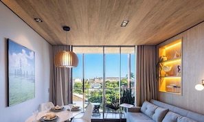 A modern living room with a large window, a dining area, and a sofa. - Studio w/ Balcony & Sea View in Condo. Nwt0413 (Maceió)