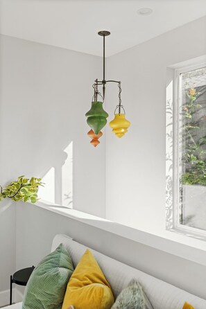 A room with a white wall, a window with a view of greenery, and a hanging light fixture with three bulbs. - Venice Beach 1-Bedroom Apartment w/ Roof Top Deck (Los Angeles)