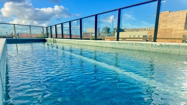 A swimming pool with clear blue water and a view of the sky and buildings in the background. - Season Smart Flats By Flat na Praia (Ipojuca)