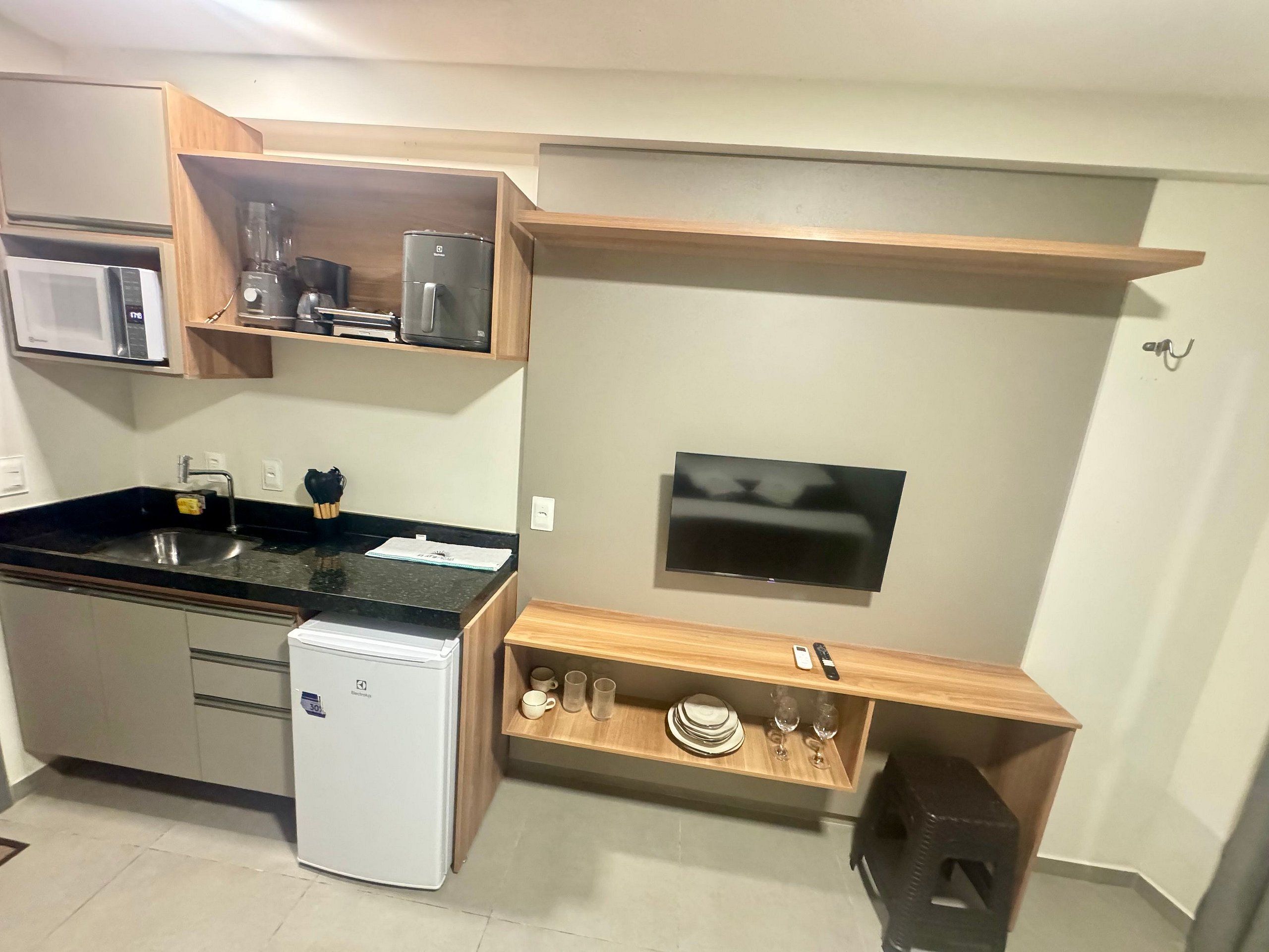 Una cocina compacta con microondas, refrigerador y horno empotrado.