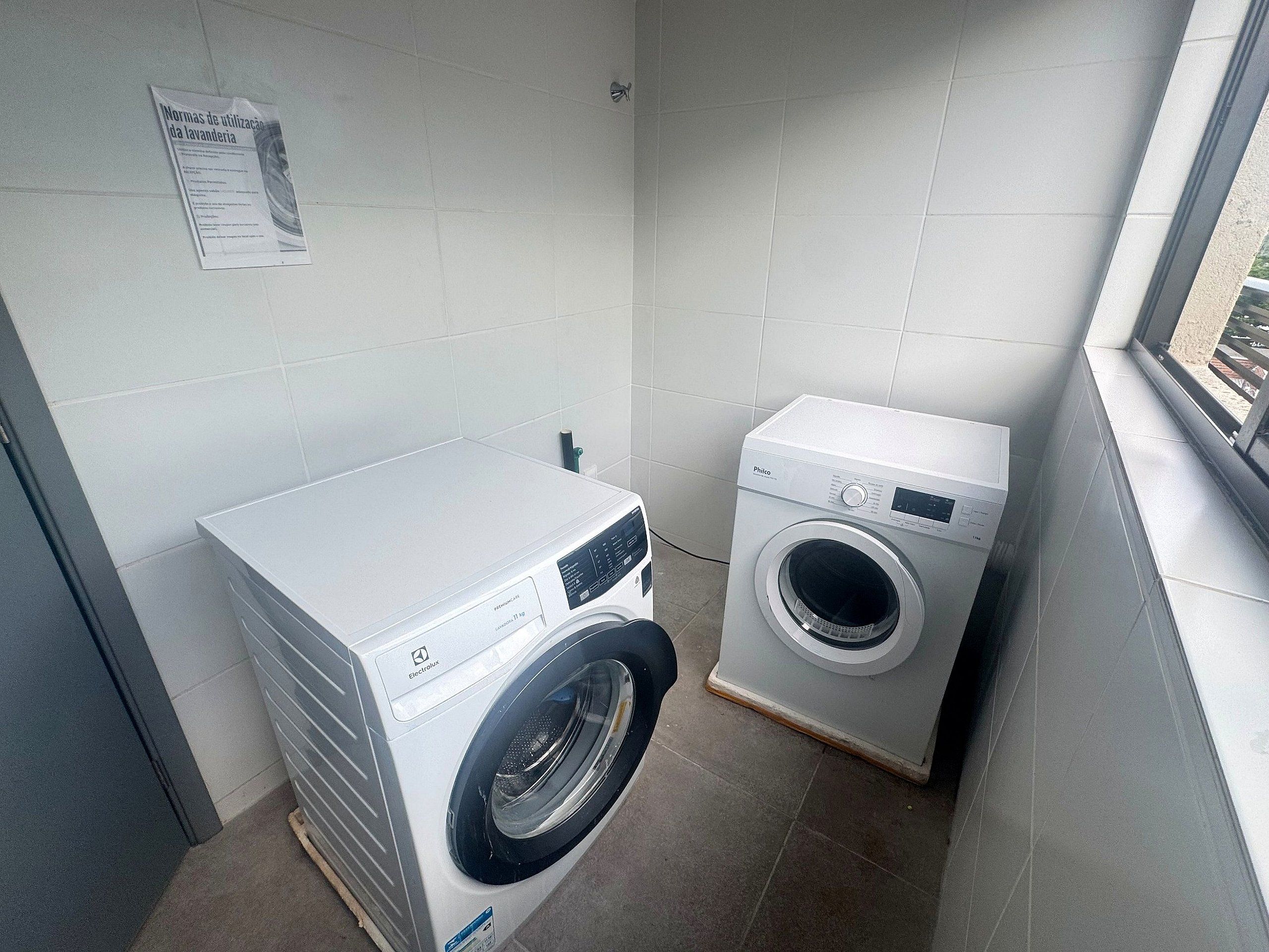 Una sala de lavandería con una lavadora de carga frontal y una secadora apilada.