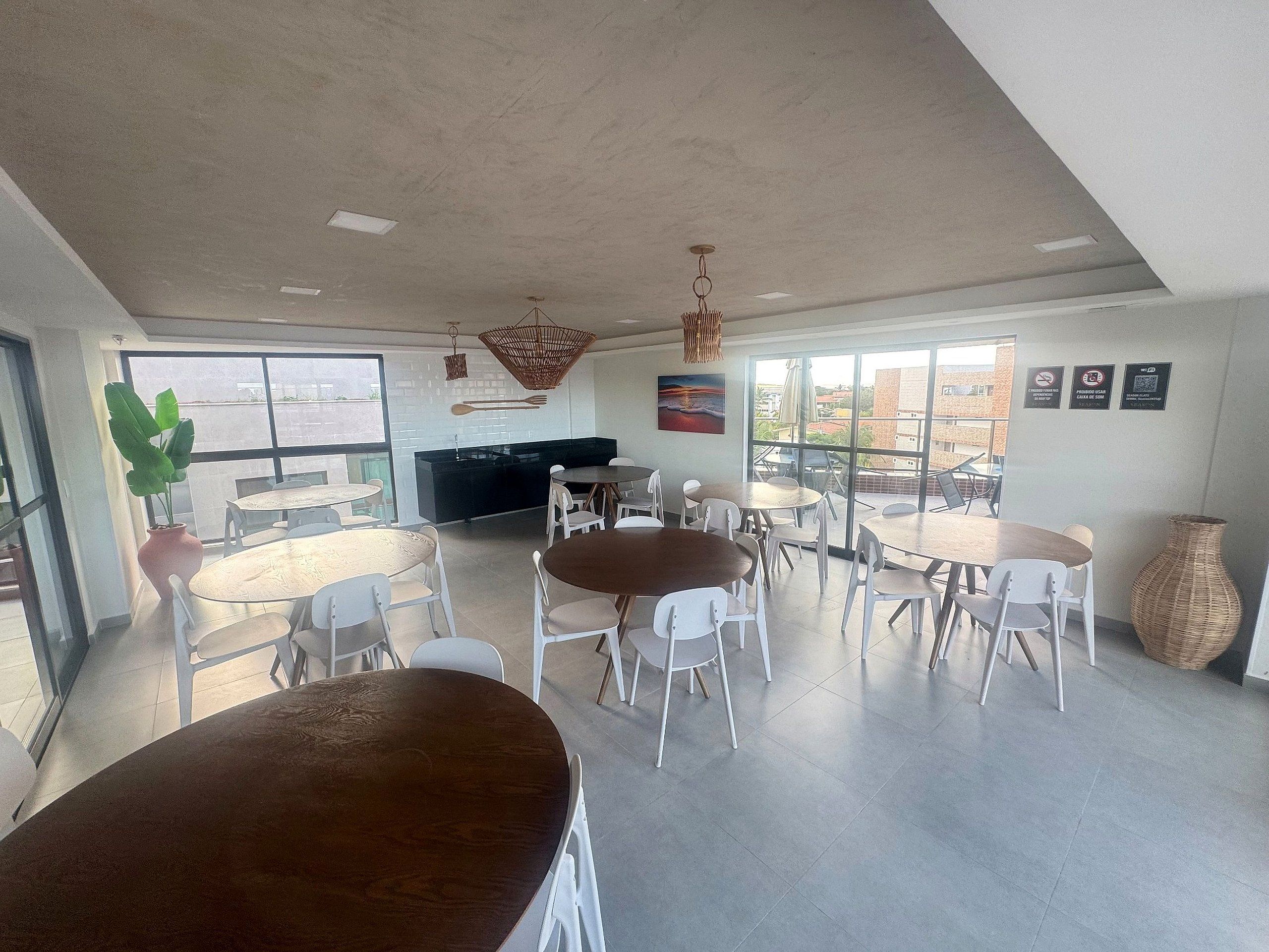 Un espace de restauration moderne avec des tables et des chaises rondes, une grande fenêtre offrant une belle vue et un îlot de cuisine noir.