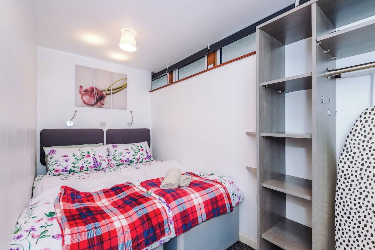 A bedroom with a bed, a wardrobe, and a wall-mounted shelf.
