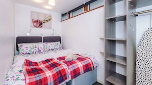 A bedroom with a bed, a wardrobe, and a wall-mounted shelf. - Cosy 1-Bed Apartment Wigan | Free Parking (Greater Manchester)