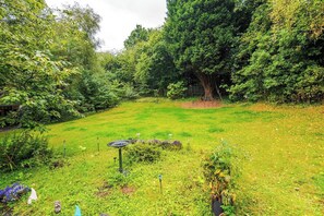 Un jardín exuberante con diversas plantas y un parterre floral circular en el centro.