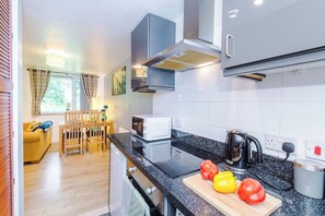 Une petite cuisine équipée d’un four à micro-ondes, d’une bouilloire et d’une planche à découper avec des légumes.