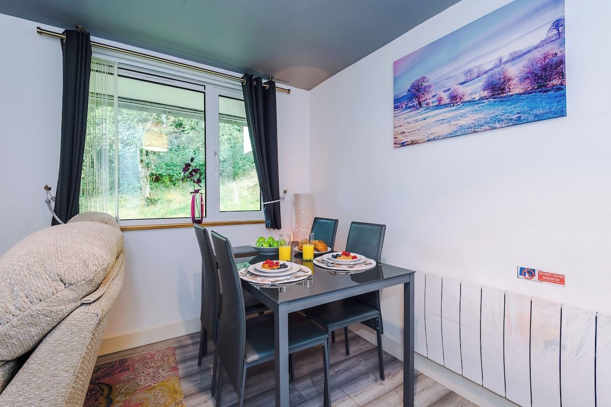 Un área de comedor con una mesa dispuesta para dos personas, un sofá y un cuadro en la pared.