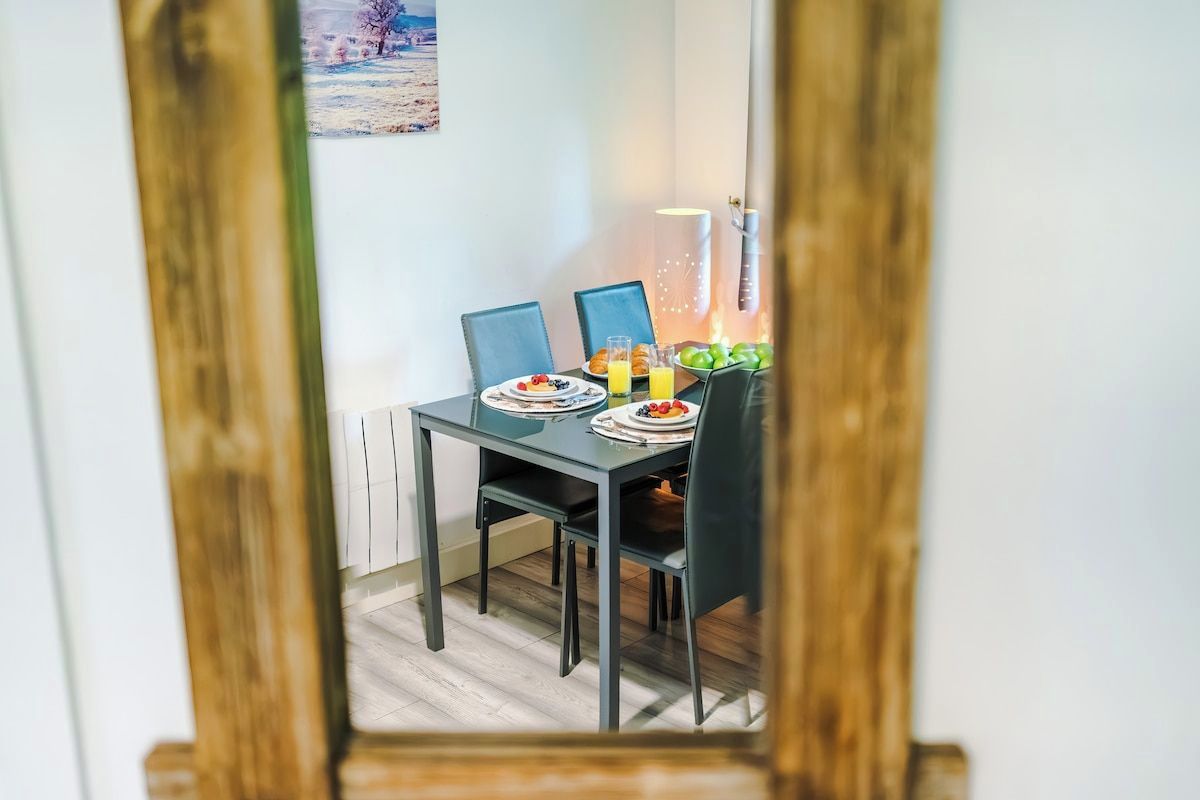 Une table à manger avec des chaises, des assiettes remplies de nourriture et un panier de fruits.