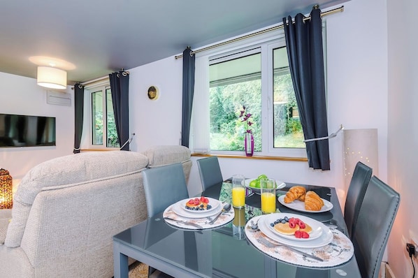 A dining area with a table set for breakfast, including plates of food, a glass of juice, and a croissant.