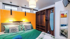 Ein Hotelzimmer mit Bett, Kleiderschrank, Pendelleuchte und einem Bild an der Wand.