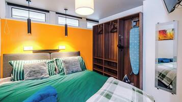 A hotel room with a bed, a wardrobe, a hanging light fixture, and a painting on the wall.