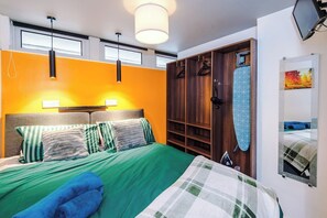 A hotel room with a bed, a wardrobe, a hanging light fixture, and a painting on the wall. - Stylish 1-Bed Apartment in Wigan | Free Parking (Greater Manchester)