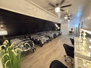 A room with a long table set up, a ceiling fan, and a vanity with lights.
