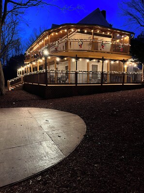 A multi-level wooden building with balconies, string lights, and a covered outdoor seating area.