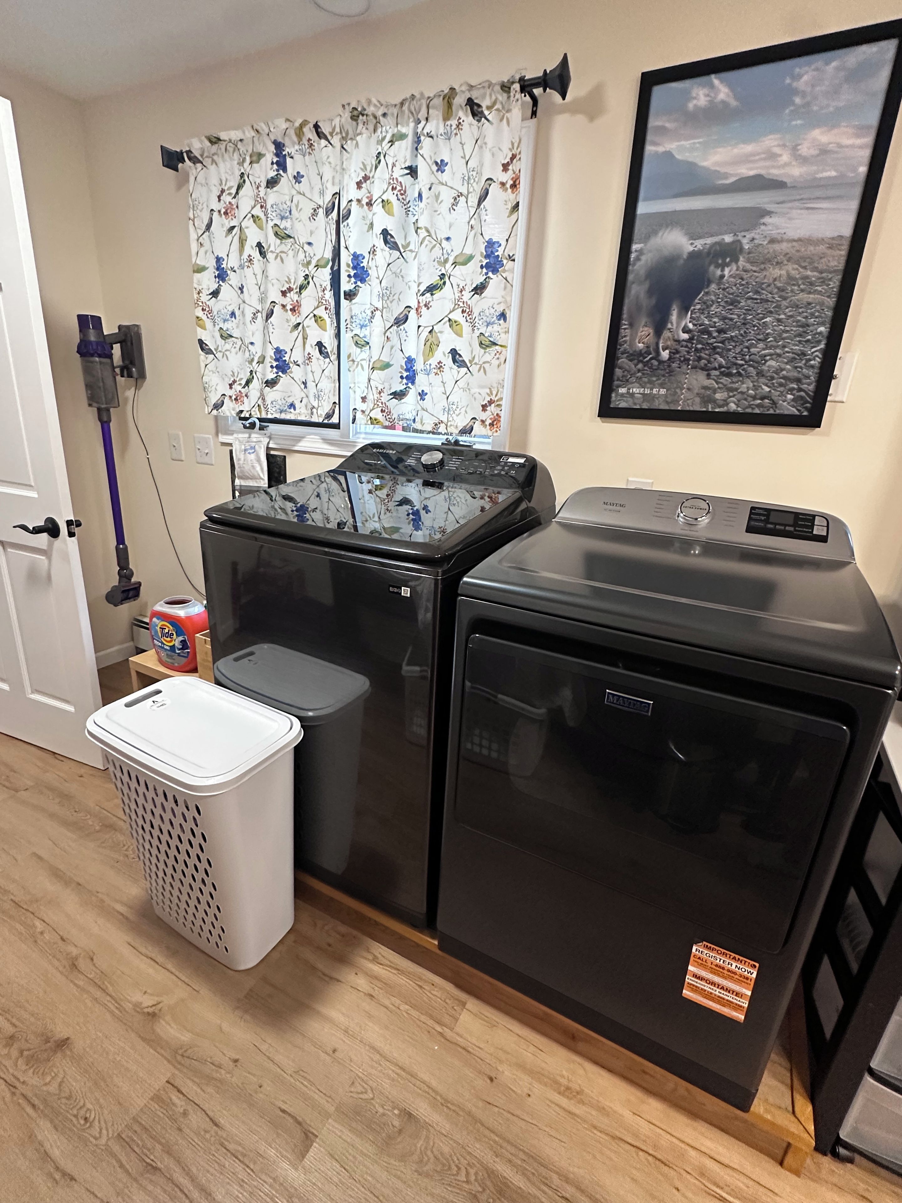 Une buanderie équipée de deux machines à laver, d’un sèche-linge, d’un aspirateur et d’un panier à linge.
