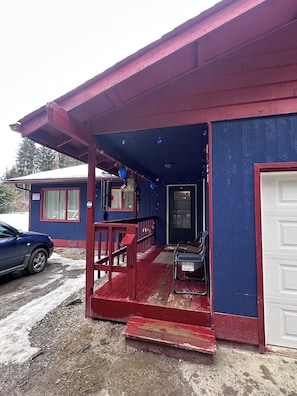 Un bâtiment avec un porche rouge, une porte et un banc.