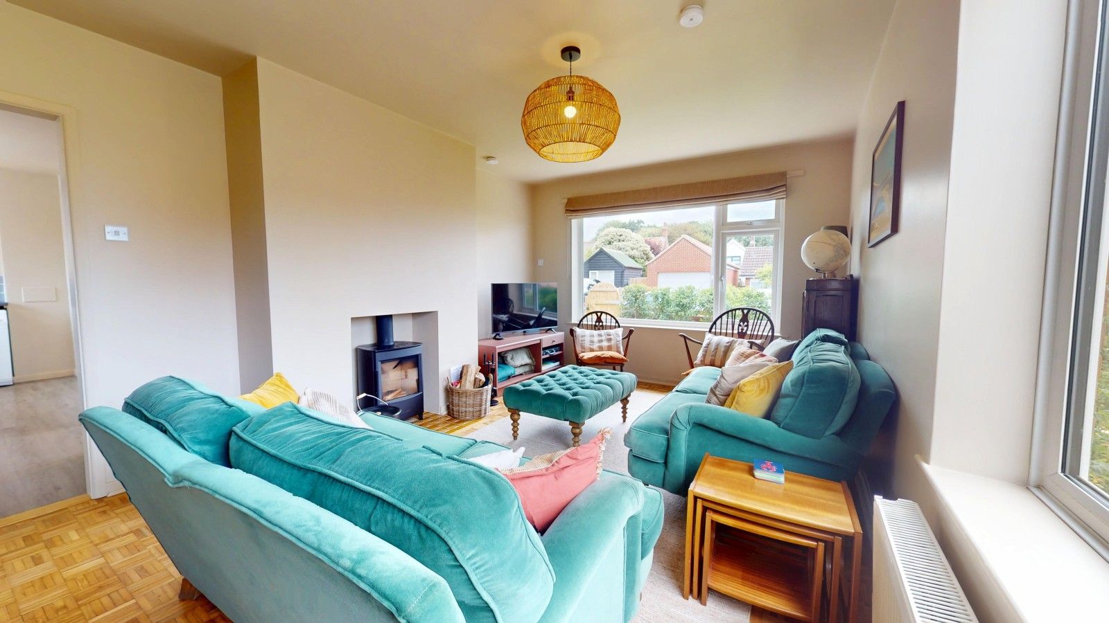 Un salon chaleureux avec des canapés de couleur turquoise, une cheminée et une grande fenêtre donnant sur l’extérieur.
