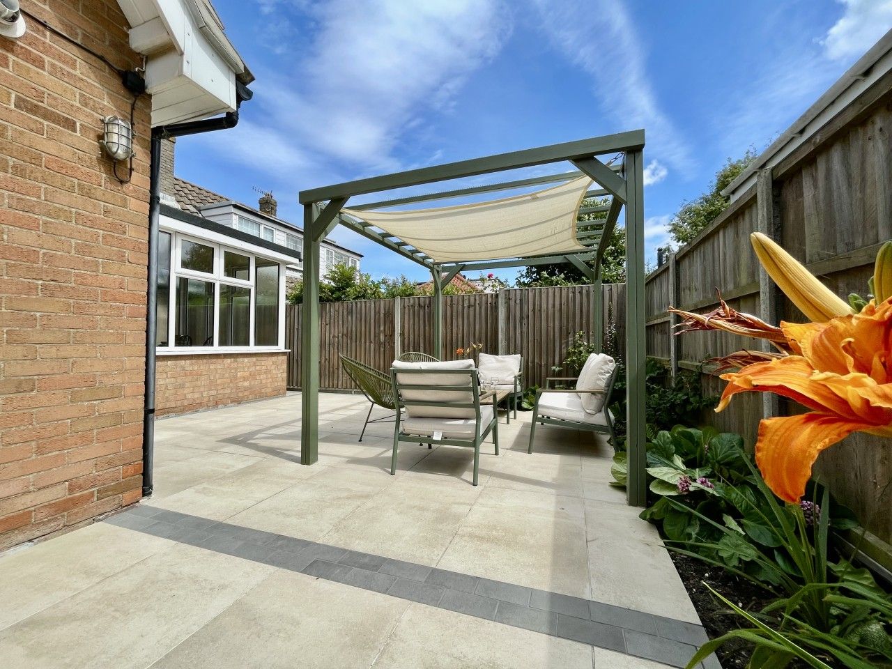 A patio area with a pergola, outdoor furniture, and a garden.
