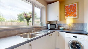 Una cocina moderna con un lavamanos doble, microondas, lavadora y una ventana con vistas al exterior.