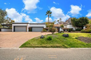 A residential area with two garage doors, a well-maintained lawn, and a clear sky. - 4-bedroom estate with 25 foot ceilings, formal salon and resort-style pool (Paradise Valley)
