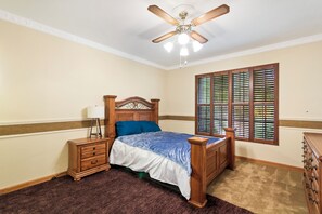 A bedroom with a wooden bed, a nightstand, a dresser, a ceiling fan, and a window with blinds. - 4-bedroom estate with 25 foot ceilings, formal salon and resort-style pool (Paradise Valley)