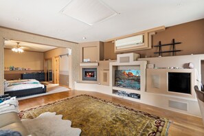 A living room with a fireplace, television, and a bed with a view to the bedroom. - 4-bedroom estate with 25 foot ceilings, formal salon and resort-style pool (Paradise Valley)