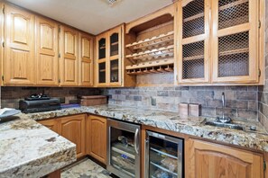 A kitchen with wooden cabinets, a granite countertop, a built-in wine rack, and a stainless steel refrigerator. - 4-bedroom estate with 25 foot ceilings, formal salon and resort-style pool (Paradise Valley)