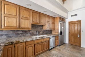 A kitchen with wooden cabinets, a stainless steel refrigerator, and a dishwasher. - 4-bedroom estate with 25 foot ceilings, formal salon and resort-style pool (Paradise Valley)