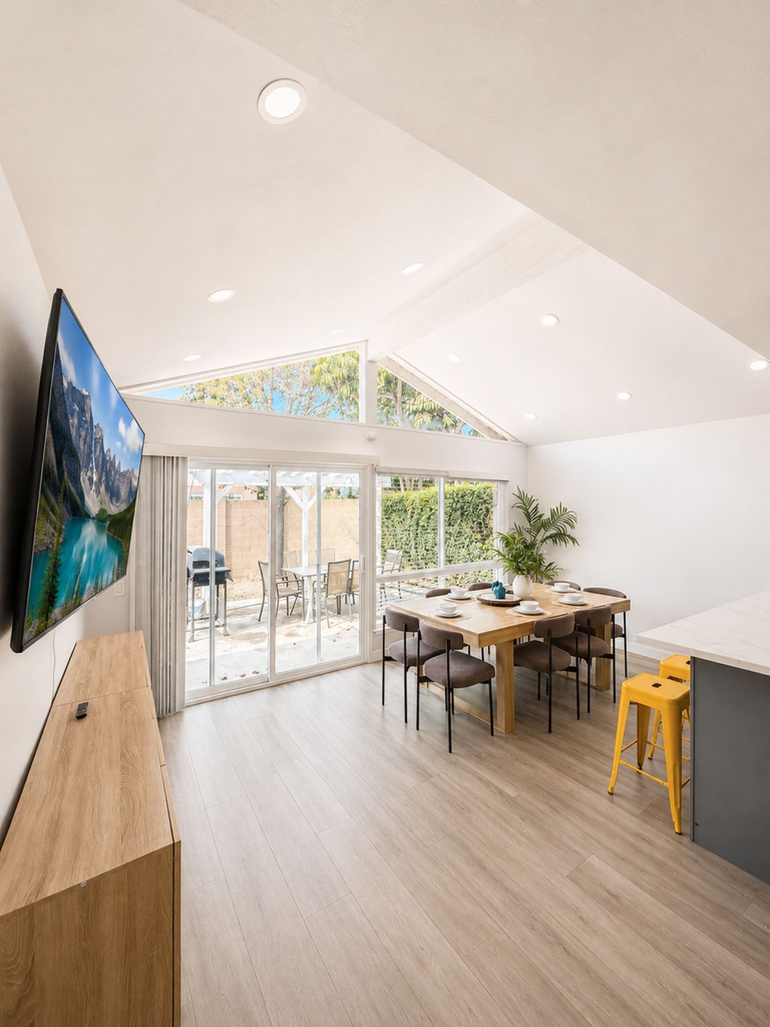 Une salle à manger spacieuse avec un plafond haut, une grande fenêtre et une vue sur l’extérieur.