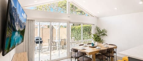 Un comedor amplio con techo alto, un ventanal y vistas al exterior.