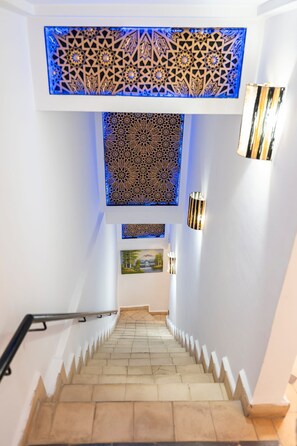 Eine Treppe mit einem gemusterten Decke und Wandverzierungen, die zu einer Ebene weiter unten führt.