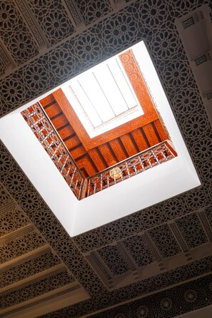 Een plafond met ingewikkelde geometrische patronen en een vierkant venster in het midden.