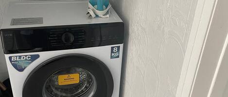 A front-loading washing machine with a BLDC motor, a warning label, and a capacity of 8 kg.