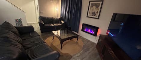 A living room with a sofa, a coffee table, a fireplace, and a television.
