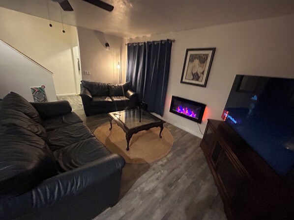 A living room with a sofa, a coffee table, a fireplace, and a television.