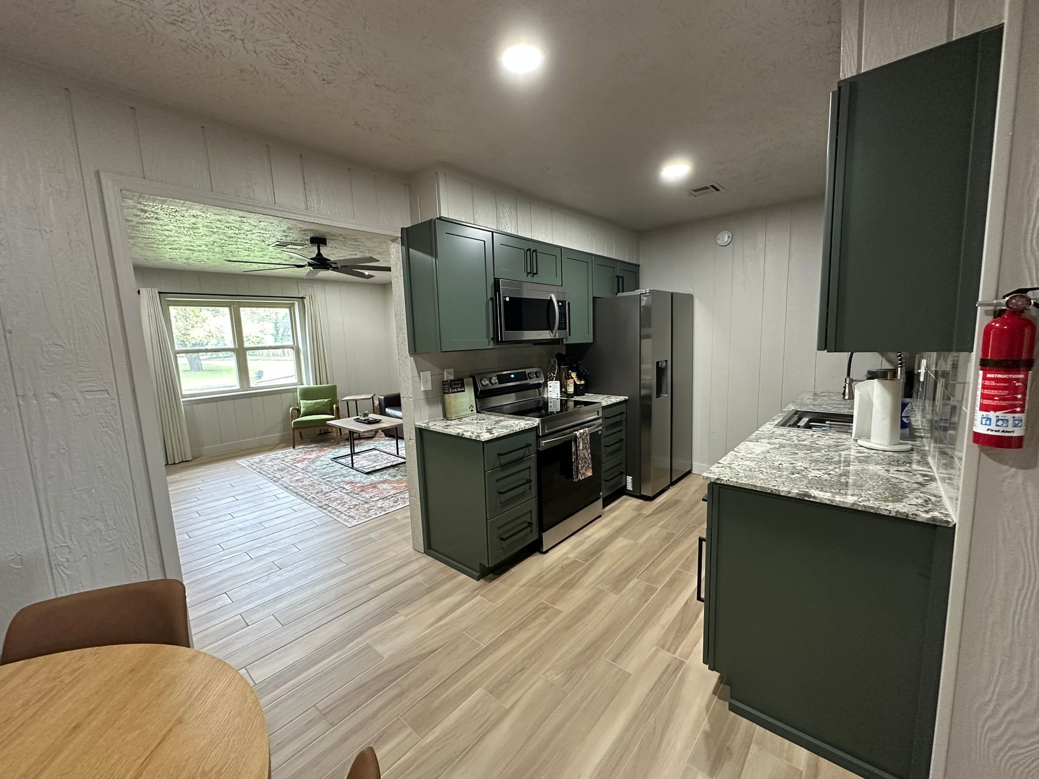 A modern kitchen with dark cabinets, a microwave, stove, and refrigerator.