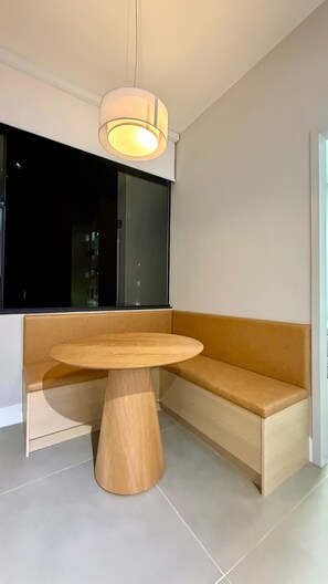 A modern interior with a round wooden table, a bench, and a large window. - Lapa RJ Space | 1.5km to Flamengo Beach (Rio de Janeiro)
