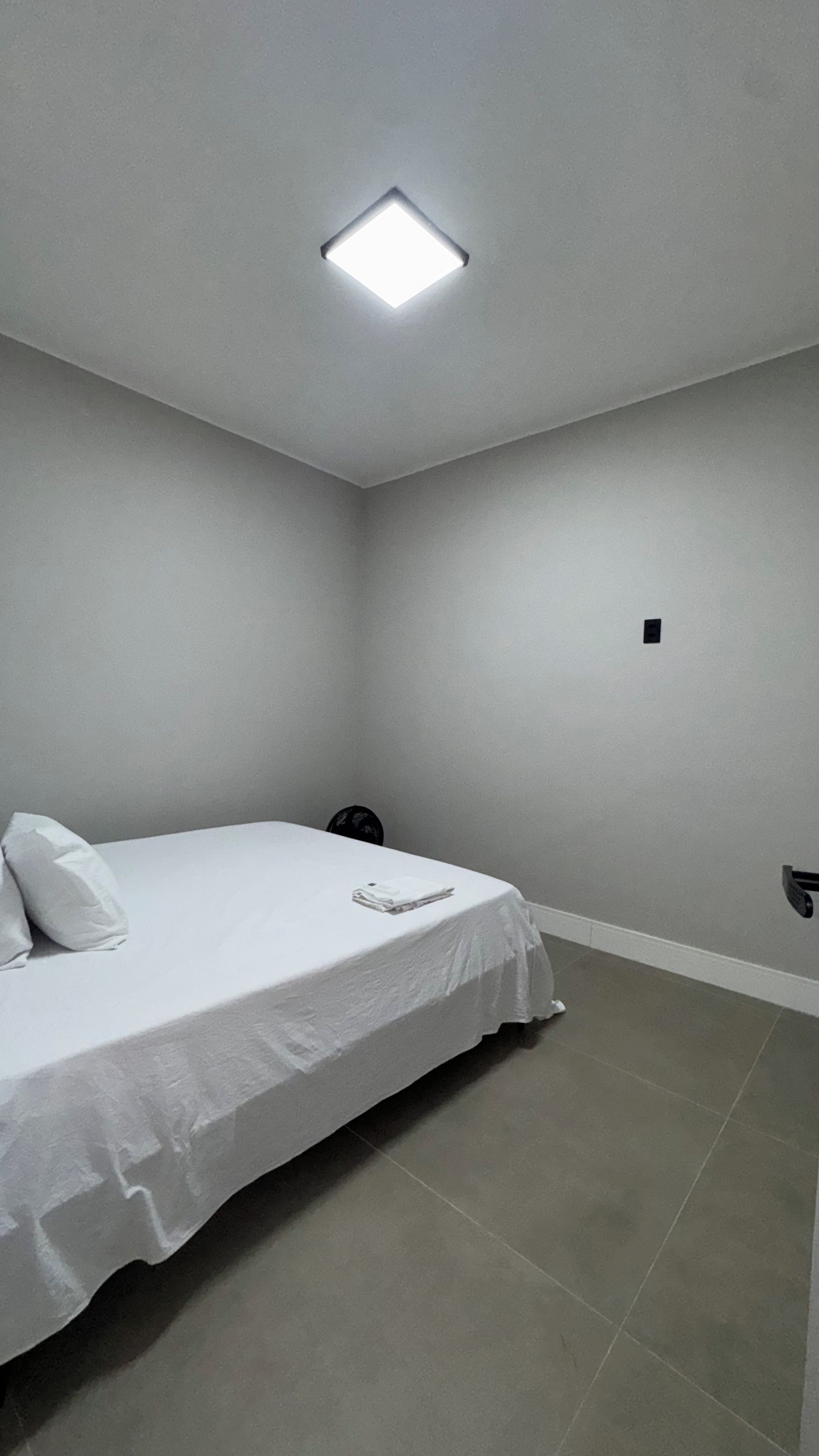Un dormitorio con cama, mesita de noche y lámpara en el techo.