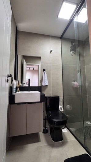 A modern bathroom with a black toilet, a white sink, and a glass shower enclosure. - Lapa RJ Space | 1.5km to Flamengo Beach (Rio de Janeiro)