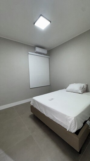 Ein Schlafzimmer mit einem Bett, einer Deckenleuchte und einer Klimaanlage.