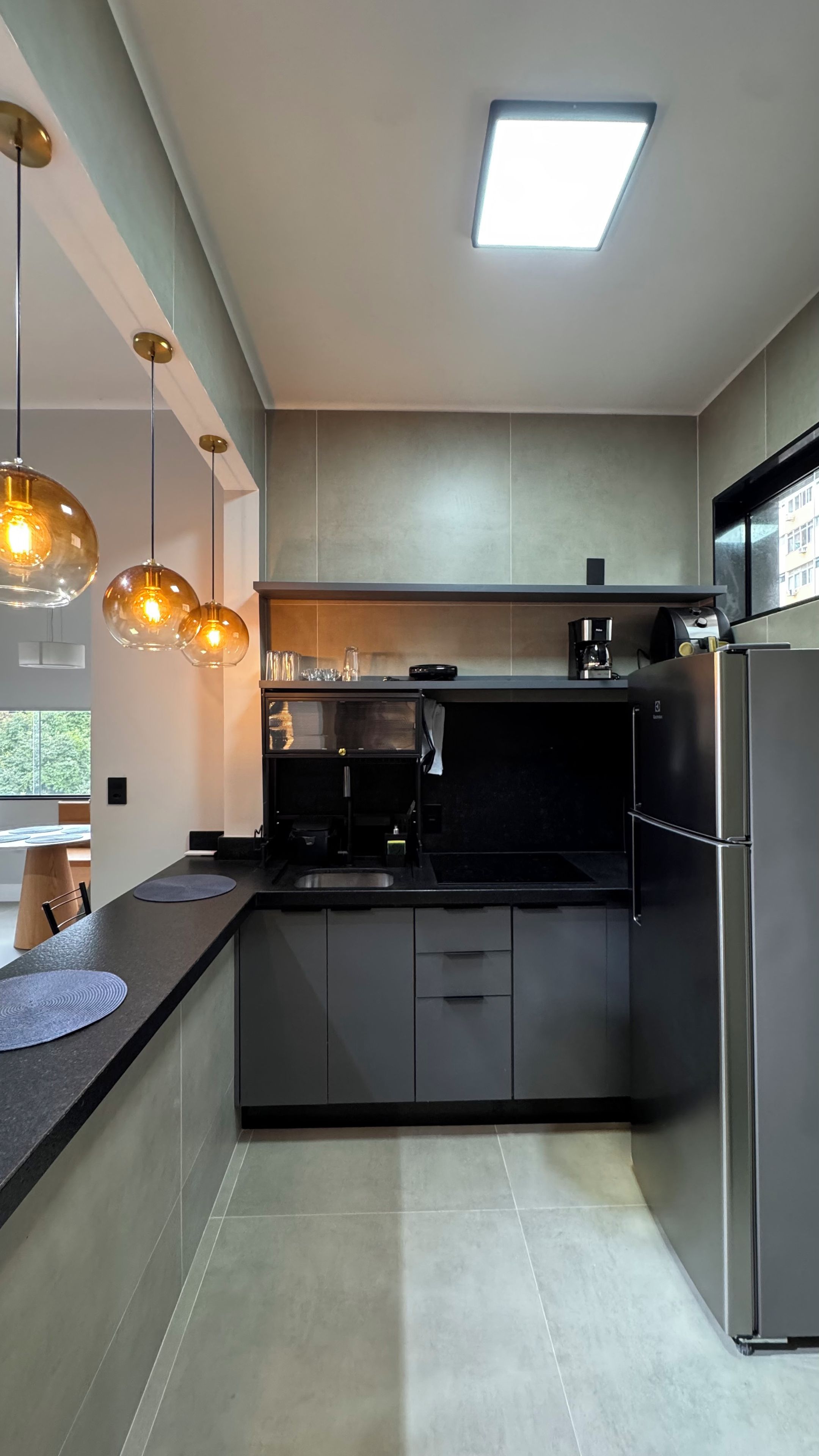 A modern kitchen with a central island, pendant lighting, and a built-in oven.