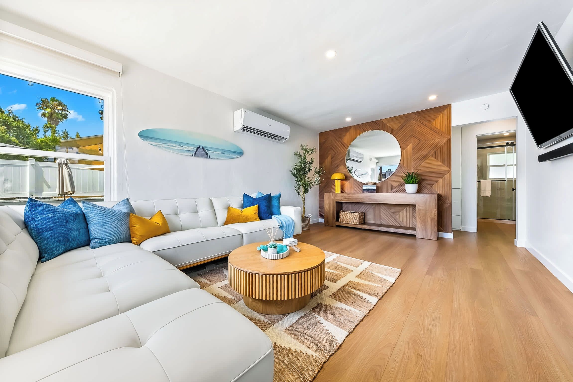 A modern living room with a white sofa, a coffee table, and a fireplace.