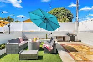 A backyard with a patio area featuring outdoor furniture, a fire pit, and a barbecue grill. - Pacific Beach Bungalow - Walk to Dine, Shop and Surf (San Diego)