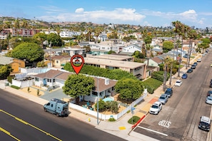 A residential area with a house featuring a front yard, a garage, and a driveway. - Pacific Beach Bungalow - Walk to Dine, Shop and Surf (San Diego)