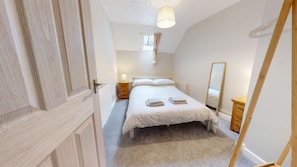 A bedroom with a bed, bedside tables, a mirror, and a window. - Newly Refurbished 2-Bed Retreat in Aylsham – Perfect for Exploring North Norfolk (Aylsham)